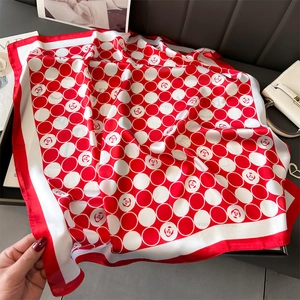 Vue détaillée d'un foulard en soie à pois rouges et fleurs sur un support luxueux