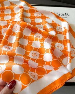 Détail d'un carré de soie avec motif camélia orange et texture soyeuse et lisse