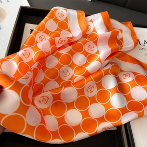 Détail d'un carré de soie avec imprimés camélia orange et motifs de maille circulaires