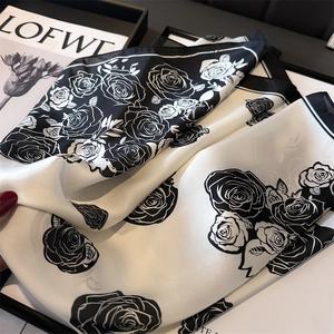 Close-up of black and white camellia floral pattern on a silky satin scarf with soft sheen