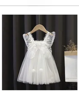 Dettaglio vestito bianco da bambina con ali di farfalla in rete e accenti di pompon