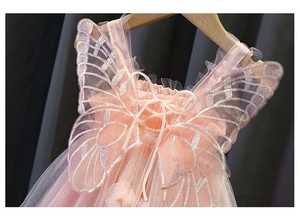 Dettaglio posteriore di un abito da principessa in tulle rosa con ali d'angelo ricamate