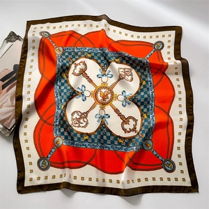 Flat lay of satin silk scarf with chain, key patterns and blue bow detail on white background