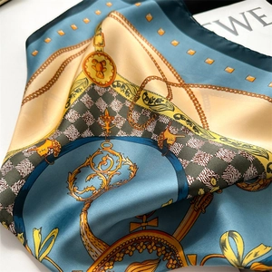 Detailed macro view of silky square scarf with vintage chain and heraldic print