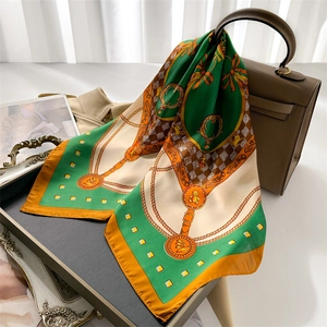 Detailed view of luxury silk scarf with chain pattern draped over a stylish handbag