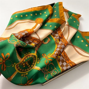 Macro detail of silk-like scarf with equestrian chain print and satin finish