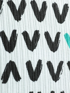 Macro view of white ribbed knit baby outfit with hand-drawn V-pattern print