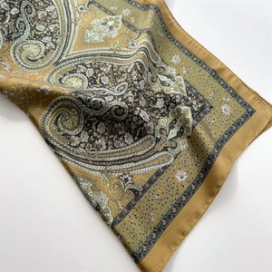 Close-up of ginger yellow paisley silk scarf with glossy texture and floral patterns