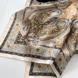Detailed macro view showing paisley floral print and silky satin texture of the scarf