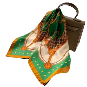 Retro chain print silk square scarf tied to a brown leather handbag on white background
