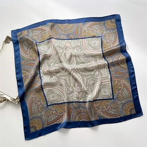 Detail of silk-like square scarf featuring blue borders and intricate paisley mandala patterns