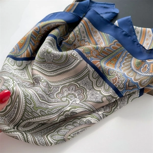 Close-up of a blue and beige paisley satin scarf showing smooth texture and vintage print