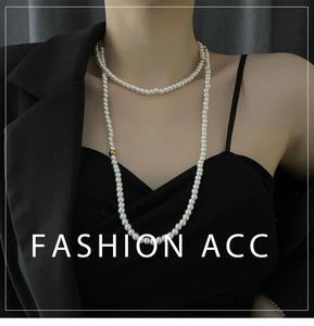 Close-up of multi-layer long pearl necklace with golden accent beads on black blazer