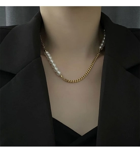 Close-up of asymmetric necklace with white pearls and gold chain on a black blazer