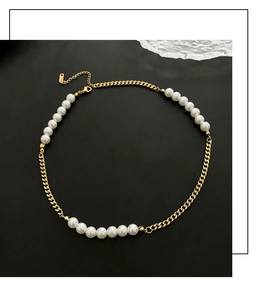 Detailed view of white pearls spliced with gold Cuban chain and delicate pendant