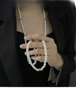 Detail of multi-layer faux pearl sweater chain with gold beads on black blazer