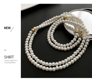 Detail of multilayer pearl necklace with gold beads and lobster clasp on black background