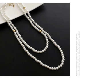 Detail showing double-layer pearl necklace with gold beads and fine metal clasp
