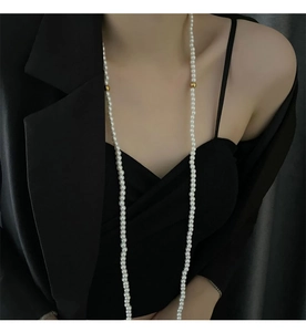 Detailed view of layered faux pearl long necklace featuring gold metallic bead accents