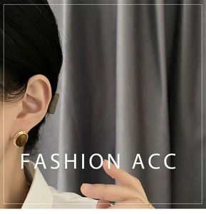 Close-up of vintage oval tiger eye stud earrings in gold finish worn by a model