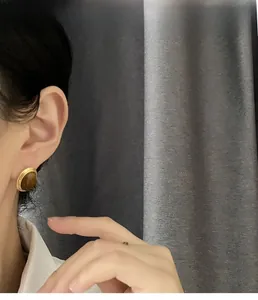 Close-up of vintage round tiger eye stud earrings with gold metal frame worn by a model