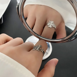 Elegant silver clover ring with hollow design shown on finger with mirror reflection