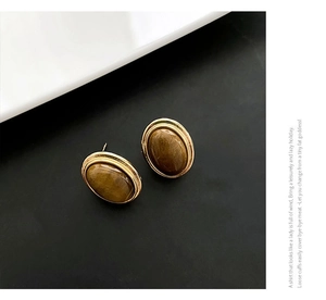 Macro detail of oval tiger eye stone earrings with vintage gold textured metal frames