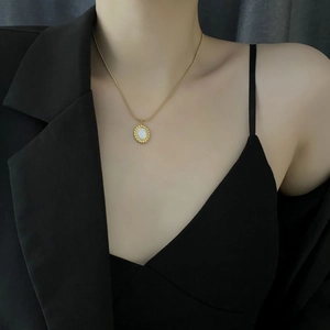 French vintage gold necklace with white mother of pearl oval pendant on black blazer