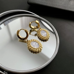 French vintage golden hoop earrings with oval mother of pearl pendants on a mirror
