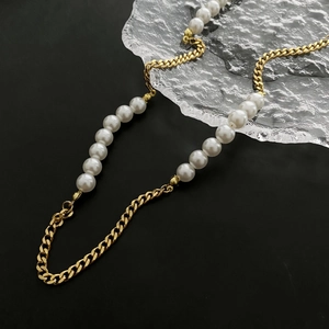 Fashionable gold Cuban chain necklace with white imitation pearls on a textured glass display