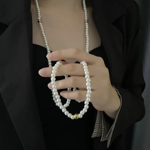Elegant multi-layer long pearl necklace with golden accents for women in chic black suit