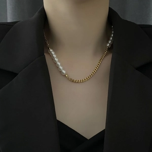 Asymmetric gold chunky chain and white pearl necklace on female model in black blazer