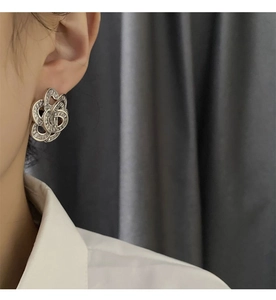Detail view of silver floral earrings with pavé zircons on a model with grey backdrop