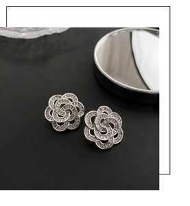 Close-up of silver floral stud earrings with sparkling zirconia in a layered design