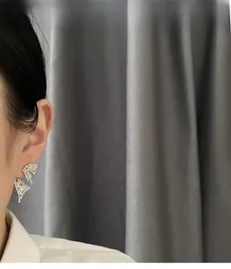 Detail of silver bow earrings with sparkling crystals worn by a model on a side view