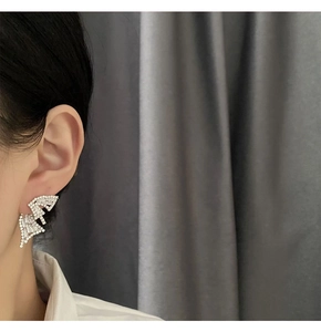 Macro detail of geometric silver earrings with pavé crystals on a model's ear