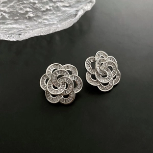 Elegant silver flower earrings with pavé crystals on a black textured background