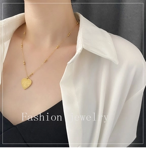 Detail of gold heart pendant with I Love You engraving on a beaded link chain