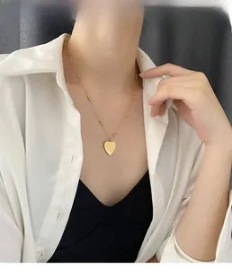 Detail of gold heart pendant necklace with I Love You engraving and beaded chain on model