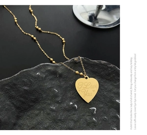 Detail of gold heart pendant necklace with I Love You engraving and tiny gold beads