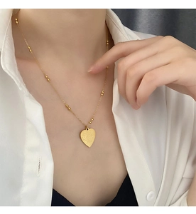 Close-up of golden heart pendant engraved with I Love You on a beaded necklace chain