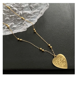 Detail of golden heart pendant with I Love You engraving on a beaded link chain