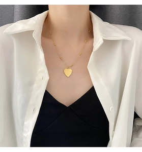 Close-up of golden heart pendant with I Love You engraving on a beaded chain necklace