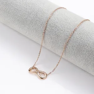 Detail of rose gold infinity pendant necklace with small crystals on a grey display