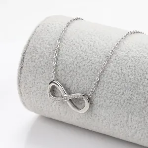 Detail of 18k gold infinity pendant necklace with cubic zirconia inlay on grey display