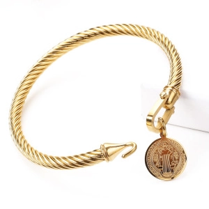 Detail of golden cable bangle featuring a religious coin pendant and twisted metal texture