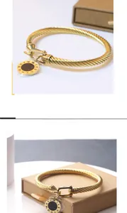 Détail d'un bracelet torsadé doré avec boucle fer à cheval et pendentif chiffres romains