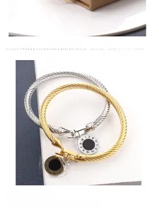 Détail de bracelets torsadés avec breloques à chiffres romains en finitions or et argent