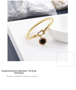 Détail d'un bracelet câble doré avec boucle en U et pendentif chiffres romains