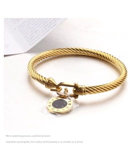 Gros plan d'un bracelet torsadé doré avec pendentif en émail noir et chiffres romains